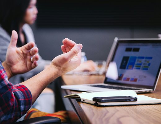 A person gesturing in conversation next to an open laptop