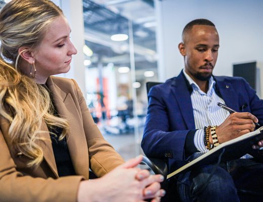 Two professionals reviewing pricing data on a clipboard